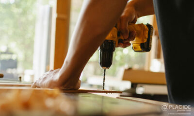 Un homme utilise une perceuse, un des nombreux outils de construction, pour percer une planche de bois en intérieur