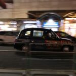 a taxi cab driving down a street at night