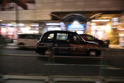 a taxi cab driving down a street at night