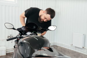 Technicien inspectant une moto sportive lors d’un entretien pare-brise moto dans un atelier.