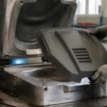 Technicien démoulant un capot en polyuréthane obtenu par moulage RIM